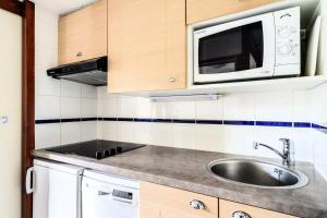 a kitchen with a sink and a microwave at Location Appartement Arzon (56640) 4 personnes in Arzon