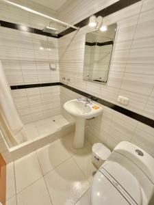 a white bathroom with a toilet and a sink at Jultom Inn Hotel & Suites in Trujillo