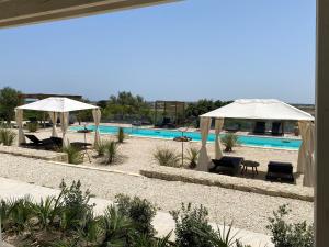 a swimming pool with two umbrellas and chairs and a swimming pool at Scilla Maris Charming Suites in Marzamemi