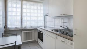 a kitchen with white cabinets and a sink and a table at Athénée 36 Résidence by Homenhancement in Geneva