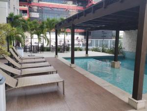 a pool in a building with chairs and tables at Mondial Apartments By BnbHost in Salvador