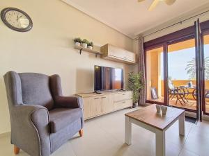 - un salon avec une chaise, une télévision et une table dans l'établissement La Serena Apartment - 3310, à Los Alcázares