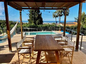 a wooden table and chairs next to a swimming pool at House with swimming pool and amazing sea and mountain views in Montgó, Denia in Denia