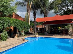 a large blue swimming pool with a red umbrella at Bougain Villa BnB in Polokwane