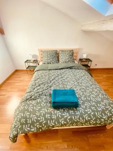 a bedroom with a large bed with a blue bag on it at Maison cosy in Courrejean
