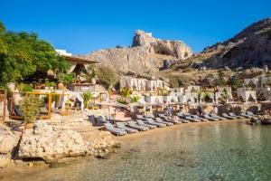 a beach with chaise lounges and chairs and a mountain at Amphitrite Villa in Gennadi