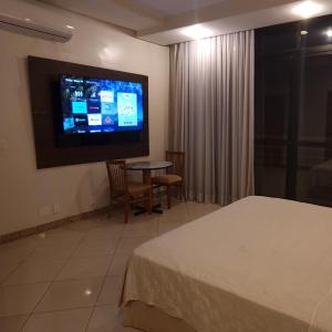 マナウスにあるCobertura Presidencial Tropical Hotelのベッド1台、壁掛けテレビが備わるホテルルームです。