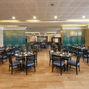 a dining room with tables and chairs in a restaurant at Dead Sea Spa Hotel in Sowayma