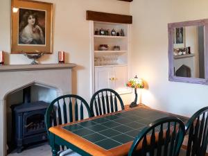 a dining room with a table and a fireplace at Rose Cottage in Grinton