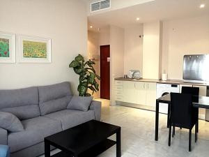 a living room with a couch and a table and a kitchen at Edificio Luxsevilla in Seville