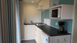 a kitchen with white cabinets and a black counter top at Camping La Touesse in Saint-Lunaire