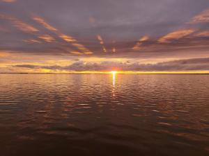 una puesta de sol sobre un gran cuerpo de agua en Ferienhaus Harmonia, en Neuendorf Heide