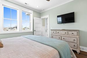 a bedroom with a bed and a flat screen tv at Fish-N-Chips by the Sea home in Holden Beach