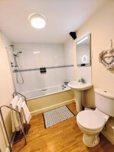 a bathroom with a toilet and a sink and a tub at Cosy Central Modern Apartment in Nantwich