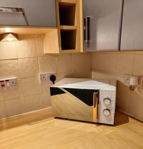 a microwave oven sitting on the floor in a kitchen at Cosy Central Modern Apartment in Nantwich