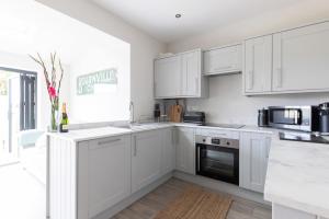 a white kitchen with white cabinets and appliances at The Old Post Office in Stocksfield