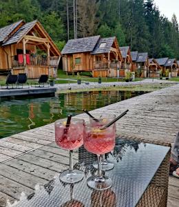 two wine glasses sitting on a table in front of a cabin at Ribno Luxury Glamping in Bled