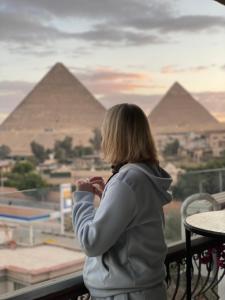une femme qui regarde les pyramides depuis un balcon dans l'établissement Unique Pyramids View INN, au Caire