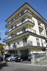 a tall white building with cars parked in front of it at Residence Igea in Rimini