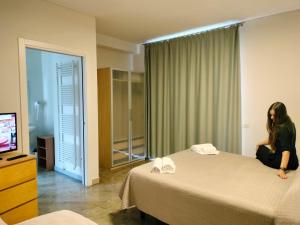 une femme assise sur un lit dans une chambre d'hôtel dans l'établissement Residence Igea, à Rimini
