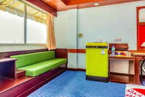 um quarto com um sofá verde e um frigorífico em OYO 441 Grand Thara Hotel em Surat Thani