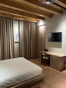 a bedroom with a bed and a desk with a television at Faces & Places Boutique Hotel in Tirana