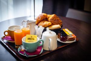 uma bandeja de alimentos e bebidas para o pequeno-almoço numa mesa em Hotel Astrid Caen centre em Caen