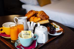 un vassoio di prodotti per la colazione e bevande su un tavolo di Hotel Astrid Caen centre a Caen