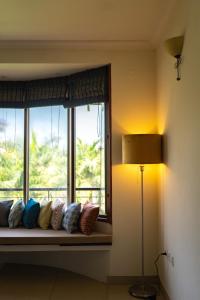a window seat with pillows sitting next to a lamp at Luho 306 in Bengaluru +74 photos