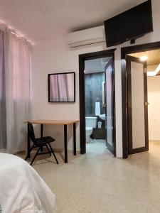 a bedroom with a desk and a table with a chair at Aparta Hotel Drake Piantini in Santo Domingo