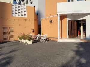 un patio con mesa y sillas frente a un edificio en Aparta Hotel Drake Piantini, en Santo Domingo