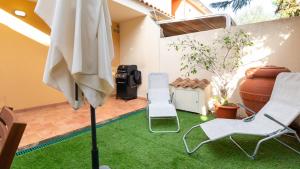 a patio with a lawn with two chairs and an umbrella at Villino Octagon in Elmas