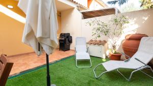 un patio con un prato con due sedie e un ombrellone di Welcomely - Villino Octagon a Elmas
