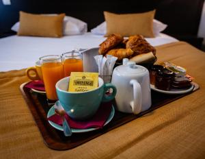 ein Tablett mit Frühstückszutaten und Getränken auf einem Bett in der Unterkunft Hotel Astrid Caen centre in Caen