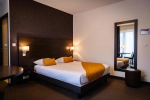 a hotel room with a bed and a table and a mirror at Hotel Astrid Caen centre in Caen