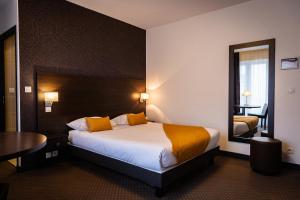 Habitación de hotel con cama, mesa y espejo en Hotel Astrid Caen centre, en Caen