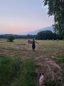 eine Person, die auf einem Feld mit einem Surfbrett läuft in der Unterkunft Pole Namiotowe Chester's Field campsite It's GENIUS! in Kampinos