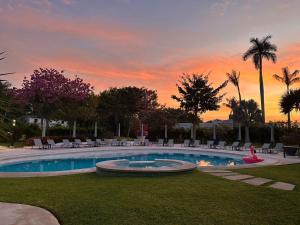 ein Pool mit Stühlen und ein Sonnenuntergang im Hintergrund in der Unterkunft Hotel Azomalli in Xochitepec