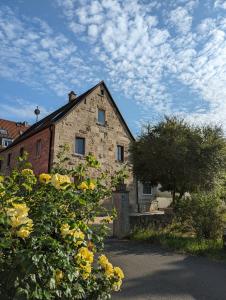 ein altes Backsteinhaus mit gelben Blumen davor in der Unterkunft Wein und Stein in Randersacker