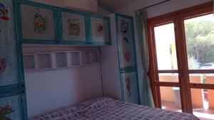 1 dormitorio con cama, ventana y puerta en Residence Isola Rossa Holiday Home Lucente, en Isola Rossa