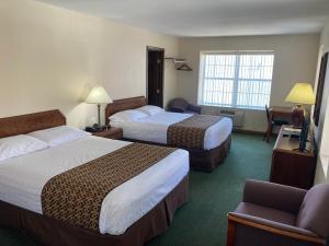 una habitación de hotel con 2 camas y una silla en The Hotel Pratt en Cooperstown