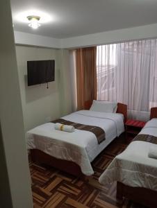 a hotel room with two beds and a flat screen tv at Posada de Mama in Cusco