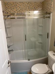 a glass shower in a bathroom with a toilet at Bellaire Midtown Cottage in Bellaire