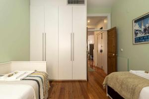 a bedroom with two beds and a large white cabinet at Pombalino Design Apartment em BaixaChiado in Lisbon