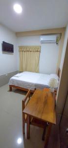Habitación pequeña con cama y mesa de madera. en Hotel Moore Iquitos, en Iquitos