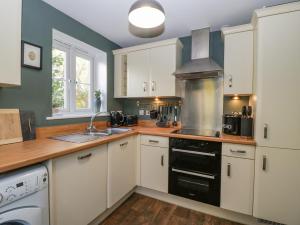 a kitchen with white cabinets and a stove top oven at 8 Barrington Mews in Ilminster
