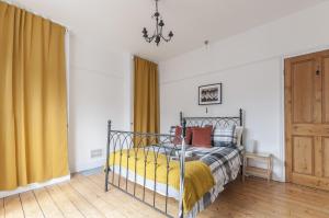 una camera da letto con un letto con tende gialle e un lampadario a braccio di Bovey House, single or king beds. Central a Exeter