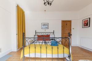 a bedroom with a metal bed with yellow and orange pillows at Bovey House, single or king beds. Central in Exeter