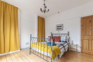 a bedroom with a bed with yellow curtains at Bovey House, single or king beds. Central in Exeter