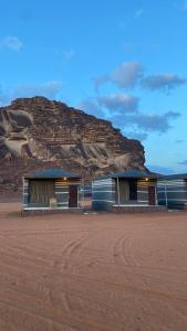 two buildings in the desert with a mountain in the background at WADi RUM NOOR CAMP in Wadi Rum